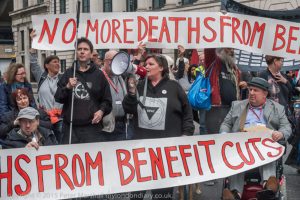 People with banners at a protest which say NO MORE DEATHS FROM BENEFIT CUTS