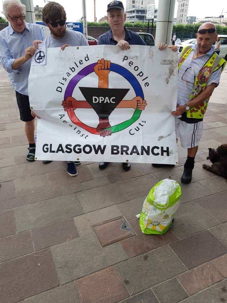 DPAC Glasgow members holding a DPAC Glasgow Branch banner at the protest