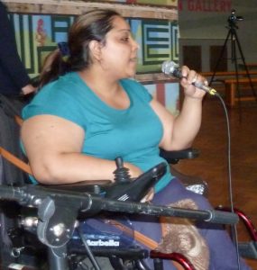 Photo of Majeet wearing a turquoise t-shirt speaking into a microphone