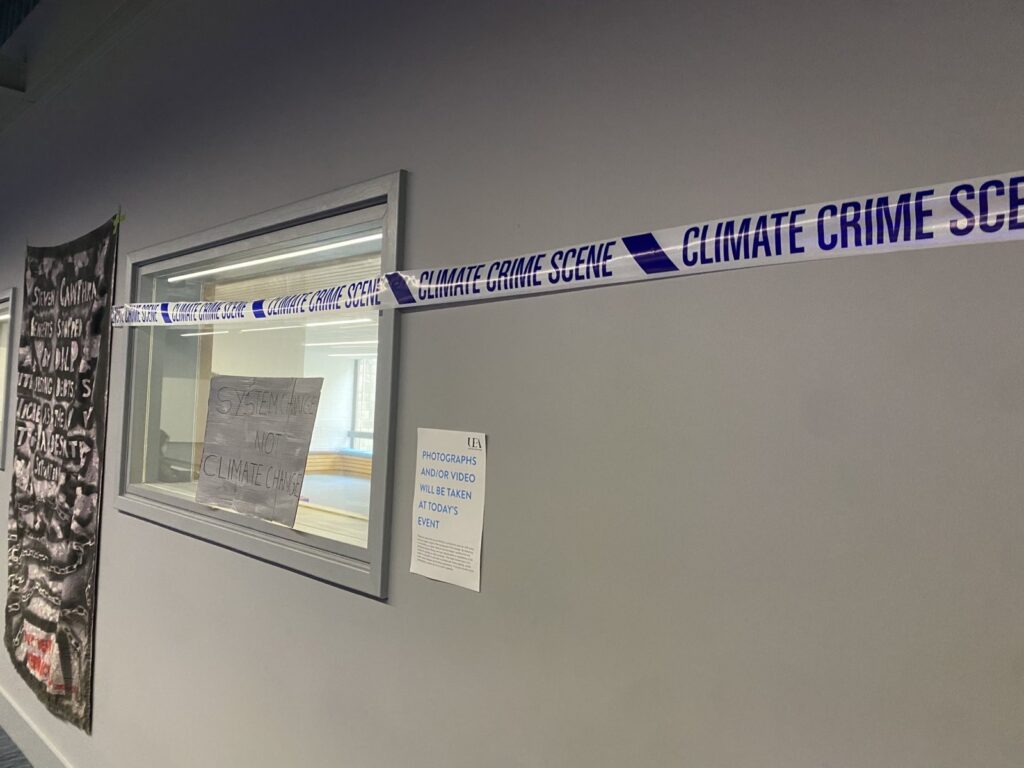 Wall at the UEA lecture theatre with a protest shroud taped to the wall, and some 'climate crime scene' tape.